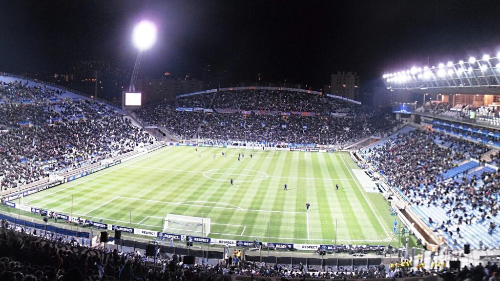 Stade de football comble sous les projecteurs lors d'un match de Ligue 1 en soirée