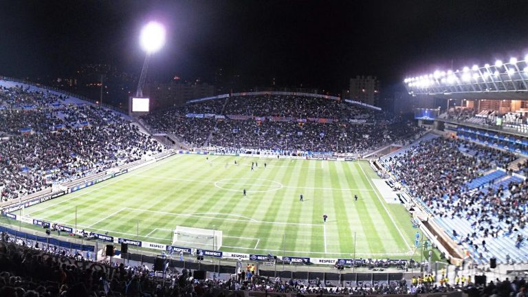 Stade de football comble sous les projecteurs lors d'un match de Ligue 1 en soirée