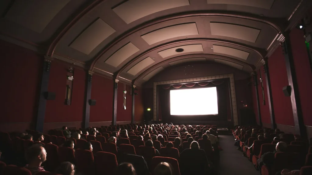 Salle de cinéma aux fauteuils rouges face à l'écran avant une projection